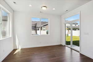 Empty room with plenty of natural light, dark wood-type flooring, baseboards, and recessed lighting