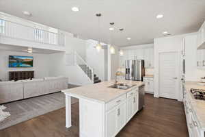 Kitchen featuring stainless steel appliances, a sink, open floor plan, light countertops, and a kitchen bar