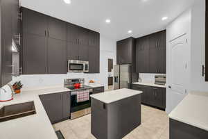 Kitchen featuring stainless steel appliances, light countertops, recessed lighting, a sink, and light tile patterned floors