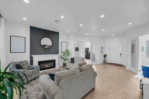 Living room with recessed lighting, a glass covered fireplace, light tile patterned floors, and baseboards