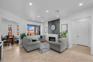 Living room featuring recessed lighting, a glass covered fireplace, and light tile patterned floors