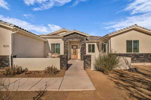 View of front of house with stone siding, stucco siding, a fenced front yard, and a tile roof