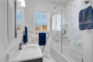 Full bath with vanity, bath / shower combo with glass door, and marble finish flooring