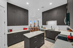 Kitchen with a sink, appliances with stainless steel finishes, light countertops, dark cabinets, and recessed lighting