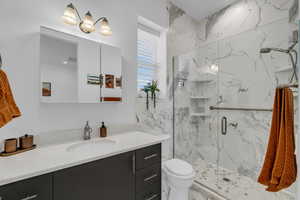 Full bathroom featuring vanity, a marble finish shower, and toilet