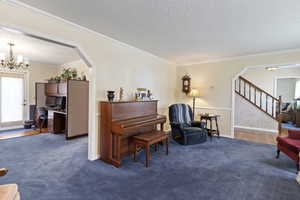 Sitting room with a textured ceiling, a chandelier, stairway, arched walkways, and an office area