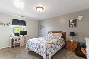 Carpeted bedroom with a textured ceiling and baseboards