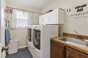 Washroom with washing machine and clothes dryer, cabinet space, sink, and baseboards