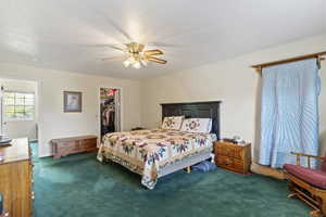 Carpeted bedroom featuring a walk in closet, ceiling fan, and a bathroom