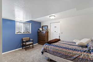 Bedroom with carpet flooring, baseboards, and a textured ceiling