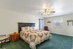 Carpeted bedroom with a ceiling fan, a textured ceiling, and baseboards