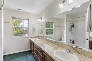 Full bathroom with double vanity, plenty of natural light, baseboards, and tub / shower combination