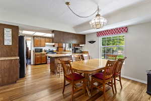 Dining space with light wood-type flooring, a textured ceiling, a chandelier, and baseboards