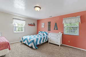 Bedroom featuring carpet, a textured ceiling, and baseboards