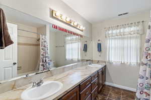 Bathroom featuring double vanity, toilet, tile patterned floors, and baseboards