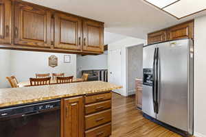 Kitchen featuring fridge, black dishwasher, light wood-style flooring, and light countertops