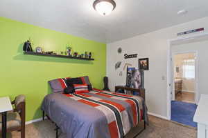 Carpeted bedroom featuring a textured ceiling and baseboards