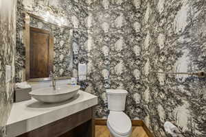 Bathroom featuring wallpapered walls, vanity, and toilet