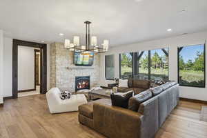 Living room with baseboards, a fireplace, light wood-style flooring, recessed lighting, and a chandelier