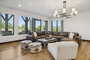 Living area with a chandelier, baseboards, light wood-type flooring, and recessed lighting