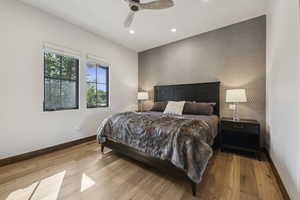 Bedroom featuring an accent wall, baseboards, recessed lighting, wood finished floors, and wallpapered walls