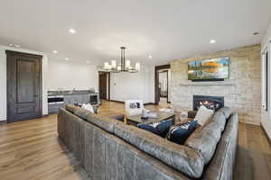 Living area with a fireplace, a chandelier, light wood-style flooring, recessed lighting, and baseboards