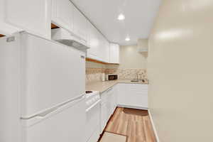 Basement newer full kitchen with modern cabinetry, sleek countertops, and white appliances