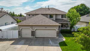 Traditional Prairie-style home with stucco and stone siding, featuring a large 3 car attached garage with RV parking, concrete driveway, and covered front porch