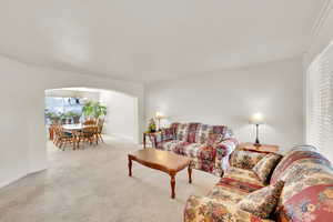 Living room and dining room area with arched walkway, plenty of natural light, neutral colors