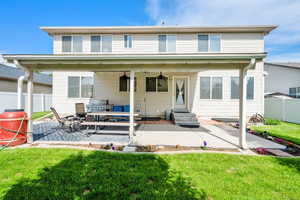 Rear view of home shows nicely designed outdoor living space, featuring a large patio area, perfect for relaxing or entertaining. Entry steps lead up to the home, while 2 ceiling fans provide a cool breeze on warm days. Roller blinds provide extra comfort