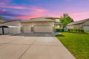Traditional Prairie-style home with stucco and stone siding, featuring a large 3 car attached garage with RV parking, concrete driveway, and covered front porch