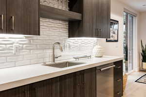 Kitchen with dark brown cabinets, open shelves, light countertops, decorative backsplash, and light wood-type flooring