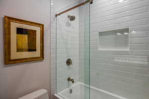 Full bathroom with bath / shower combo with glass door and toilet