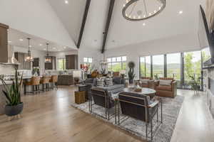 Living room featuring a chandelier, high vaulted ceiling, recessed lighting, light wood-style flooring, and a fireplace