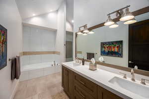 Full bathroom with a garden tub, double vanity, and high vaulted ceiling