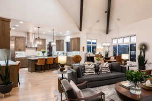 Living room with a chandelier, high vaulted ceiling, light wood-style floors, beamed ceiling, and recessed lighting