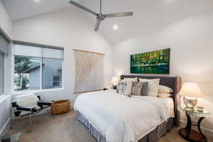 Carpeted bedroom with high vaulted ceiling and a ceiling fan