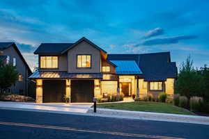 View of front of home with a standing seam roof, a metal roof, a garage, driveway, and a yard