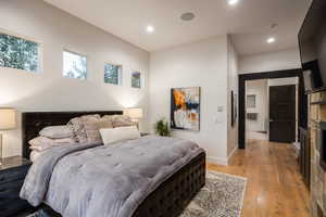 Bedroom with light wood-style floors, a fireplace, and recessed lighting