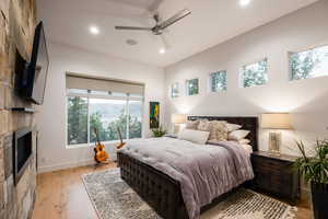 Bedroom featuring multiple windows, light wood-type flooring, a fireplace, recessed lighting, and a ceiling fan