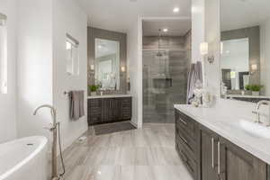 Bathroom with a stall shower, two vanities, and a freestanding bath