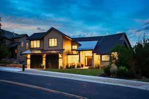 Modern inspired farmhouse featuring a standing seam roof, a metal roof, an attached garage, driveway, and a yard