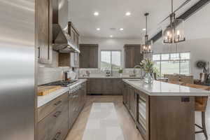 Kitchen with light wood finished floors, stainless steel appliances, a breakfast bar, tasteful backsplash, and recessed lighting
