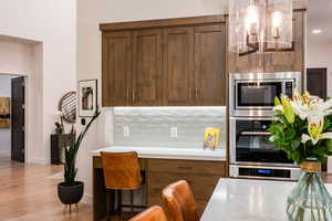 Kitchen featuring backsplash, stainless steel appliances, light countertops, and light wood finished floors