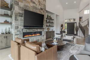 Living area with wood finished floors, built in features, stairway, a high ceiling, and plenty of natural light