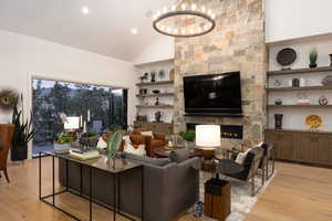 Living room featuring high vaulted ceiling, light wood-style flooring, a fireplace, built in shelves, and recessed lighting