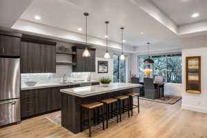 Kitchen featuring open shelves, a tray ceiling, light countertops, backsplash, and freestanding refrigerator