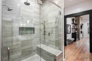 Full bathroom featuring a shower stall, wood finished floors, and a large fireplace