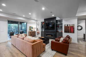 Living room featuring a fireplace, light wood-style floors, recessed lighting, and built in shelves