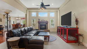 Living room featuring a stone fireplace, a chandelier, baseboards, ceiling fan, and recessed lighting